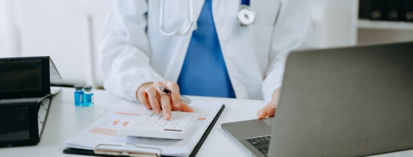 Doctor using calculator and notebook