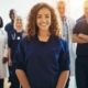 A smiling healthcare worker stands with a team of hospital staff